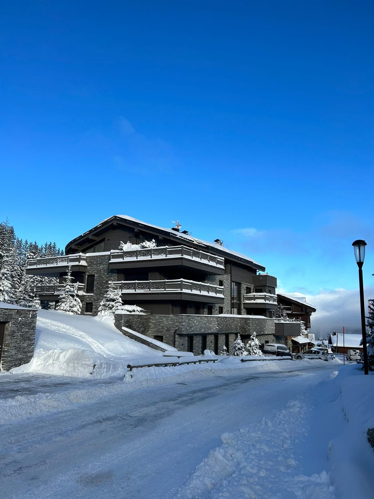 Un chalet de piedra y madera bajo la nieve recién caída y un cielo azul intenso en Courchevel